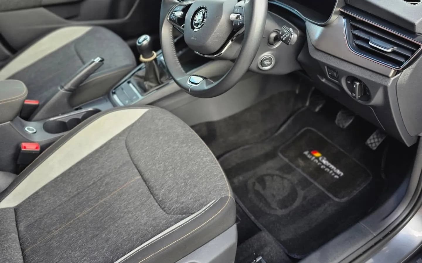 Grey fabric driver's seat, steering wheel and carpet floor mat inside a car after a VDS clean
