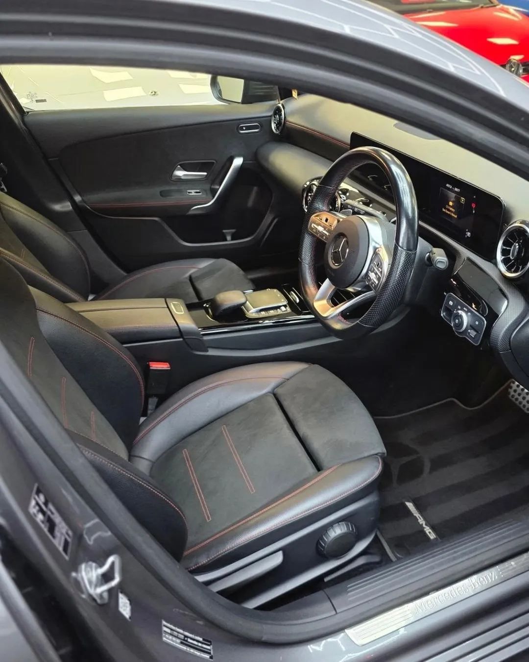 Car interior after a VDS clean, seen through the open driver's door: black seats with red stitching, dashboard and floor mats