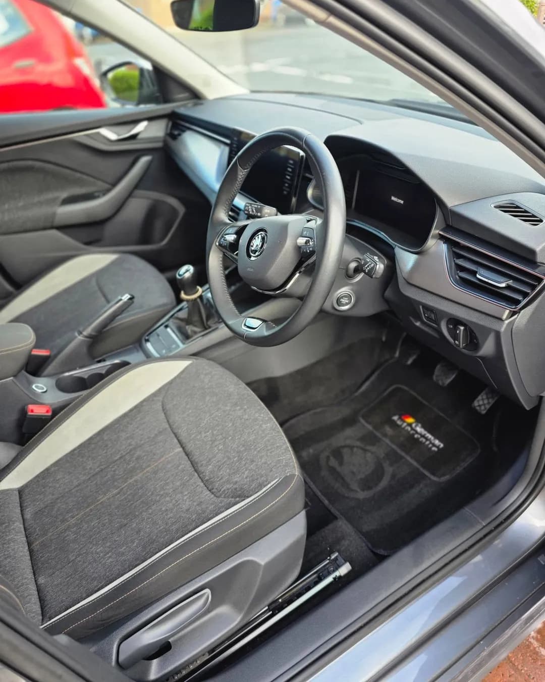 Fabric front seats, dashboard and carpet floor mats after a VDS clean, seen through the open driver's door