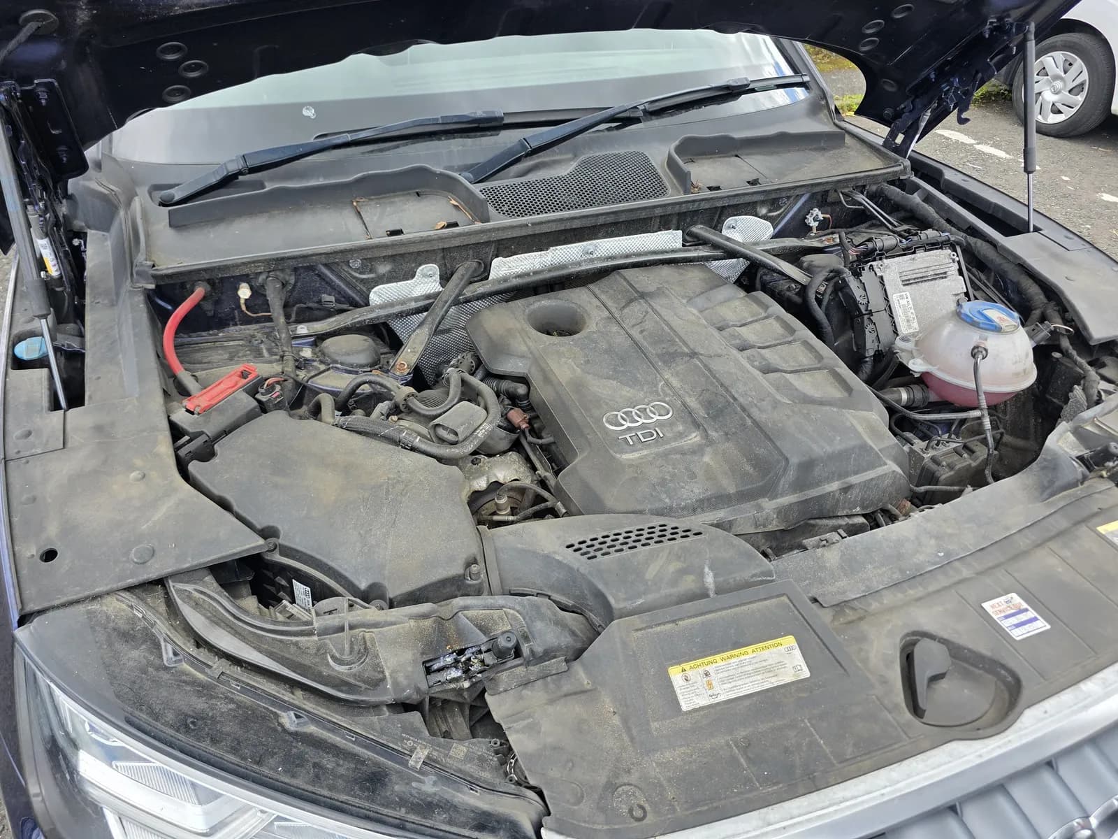 Audi TDI engine bay covered in a grey film of road dirt and dust before cleaning